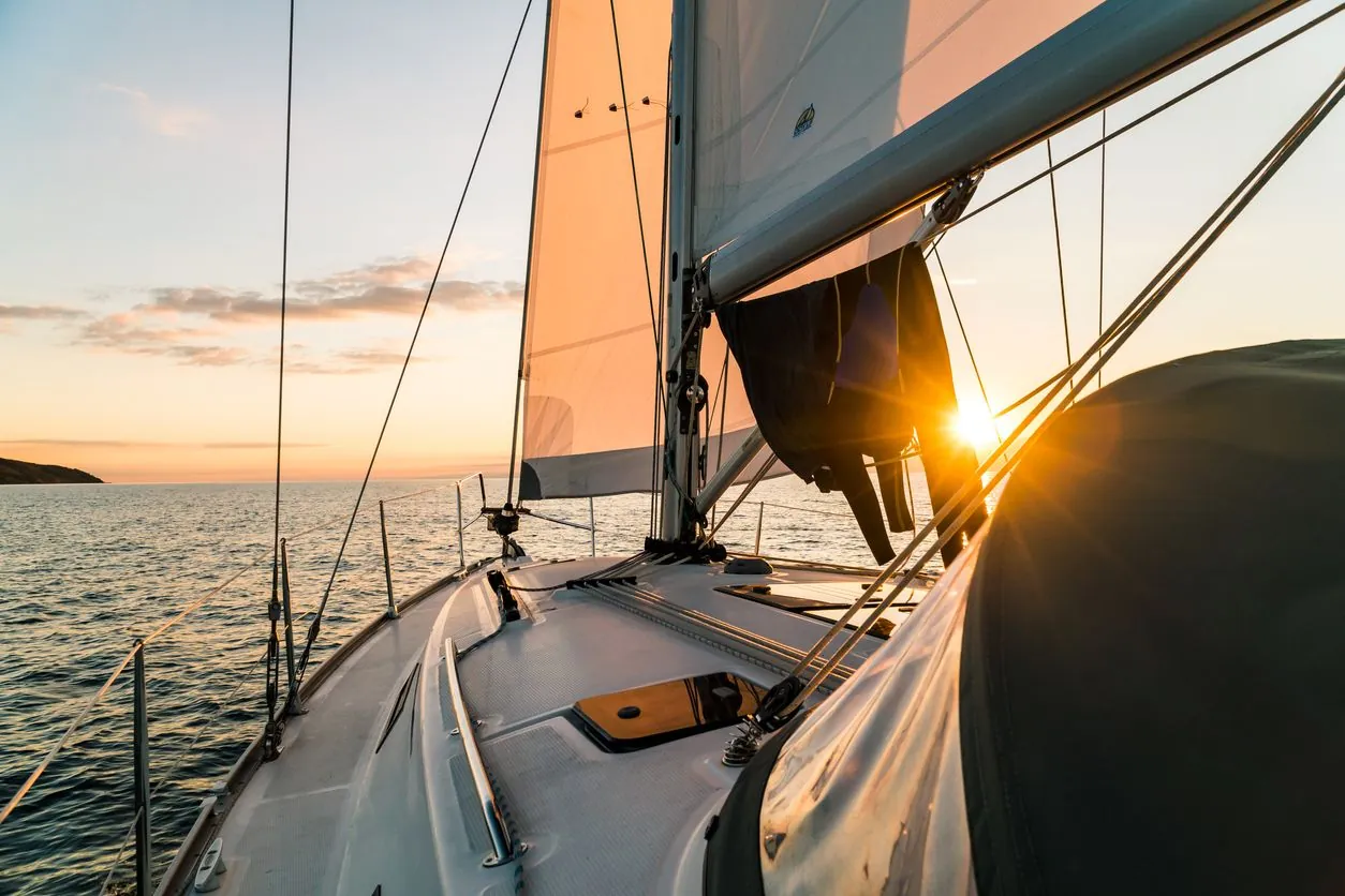 Bug eines Segelboots im Licht der untergehenden Sonne, der Blick geht über das offene Meer zum Horizont